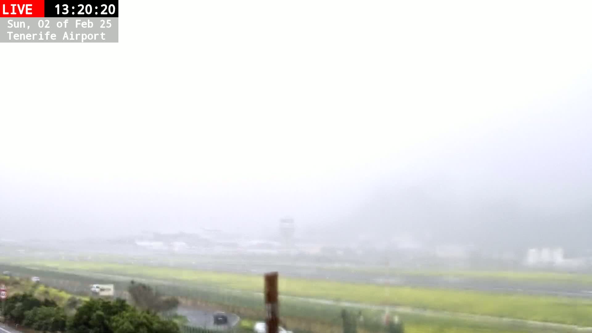 A foggy view of an airport runway and surrounding landscape is visible from a distance.