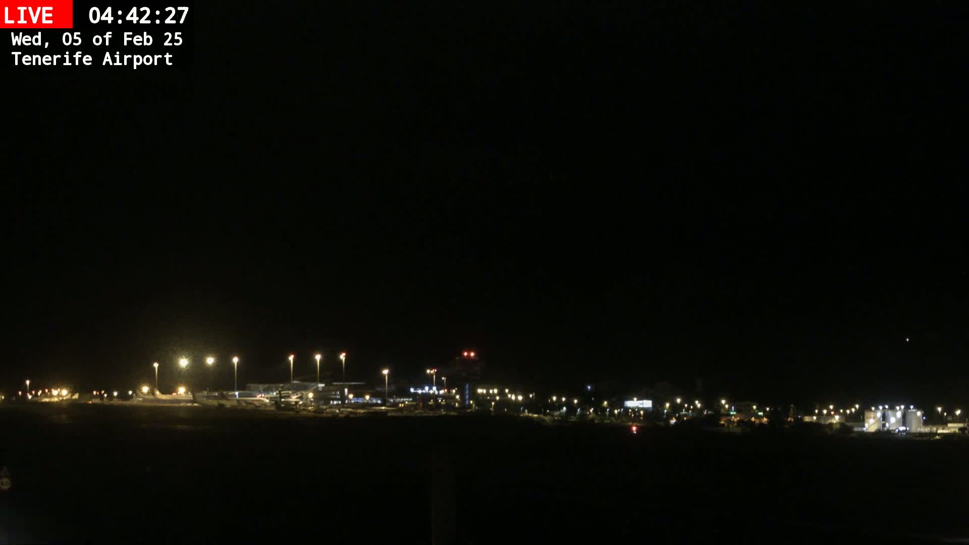 A dark nighttime view of an airport illuminated by numerous lights.
