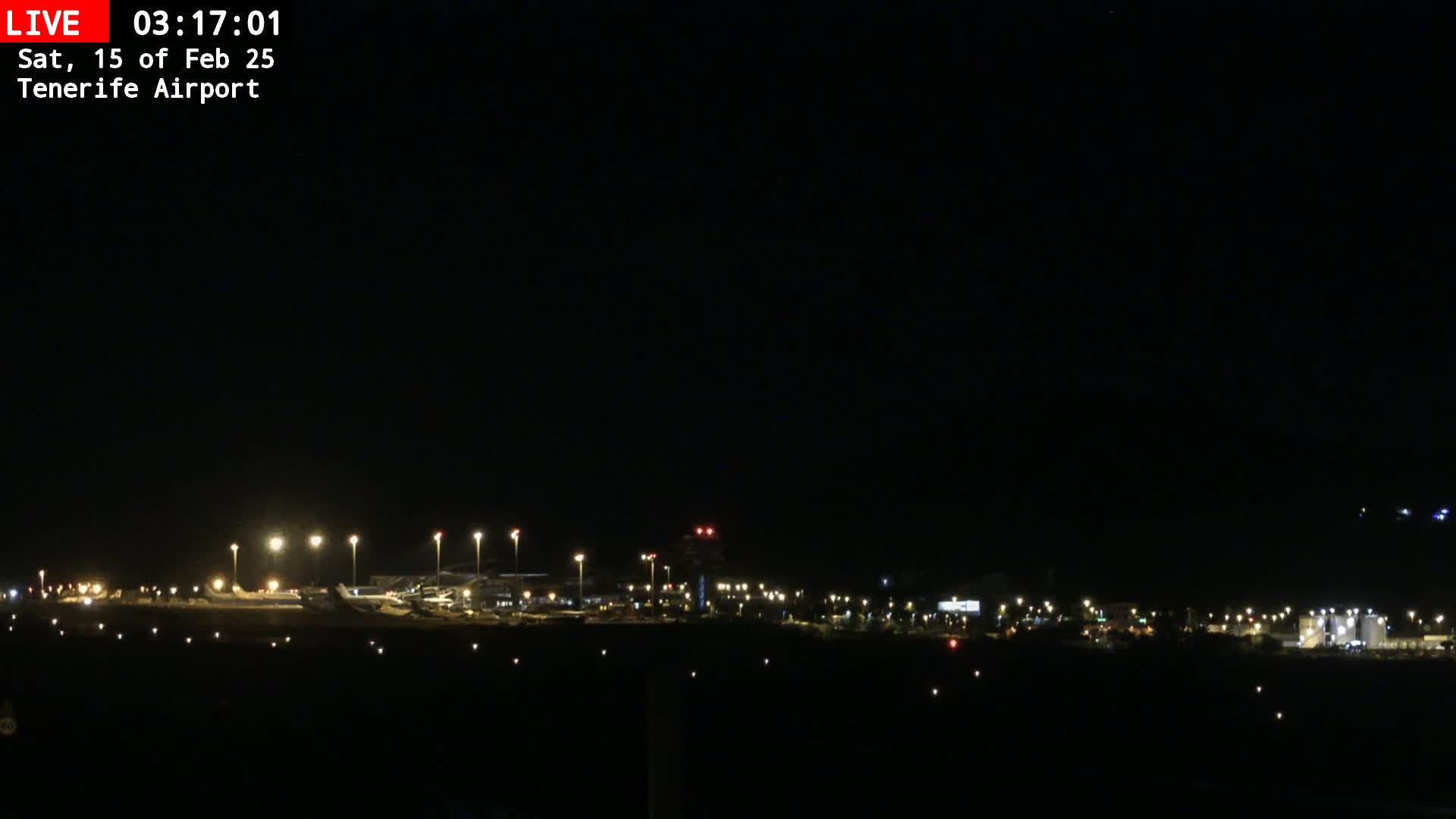 A nighttime long shot of an airport illuminated by many lights under a clear, dark sky.