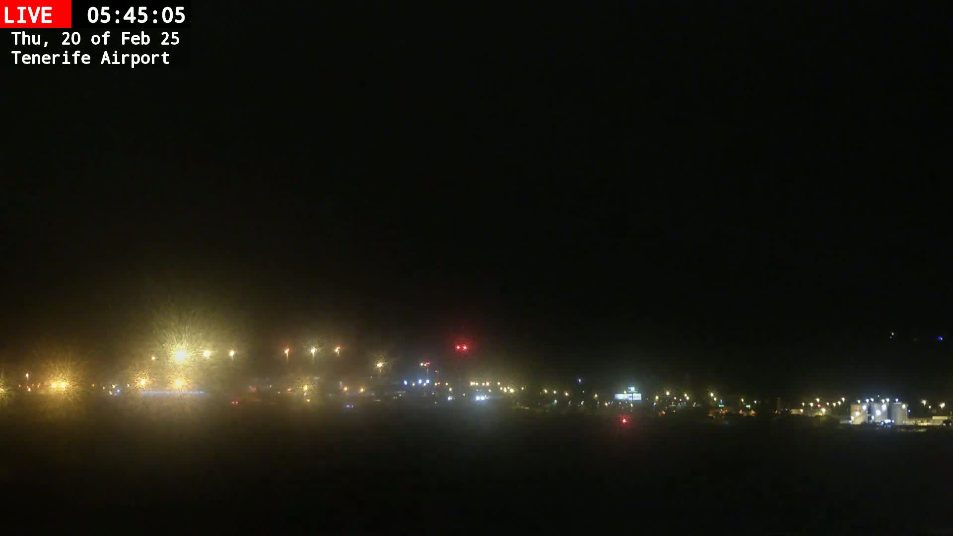 A hazy, dark nighttime scene shows distant airport lights through a light fog or mist.