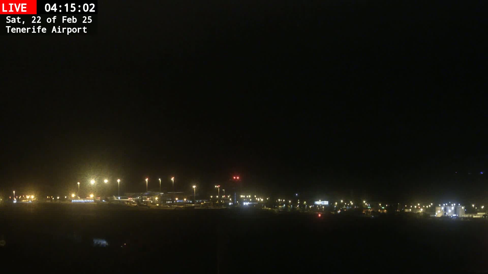 A nighttime long shot of an airport illuminated by lights under a dark sky.