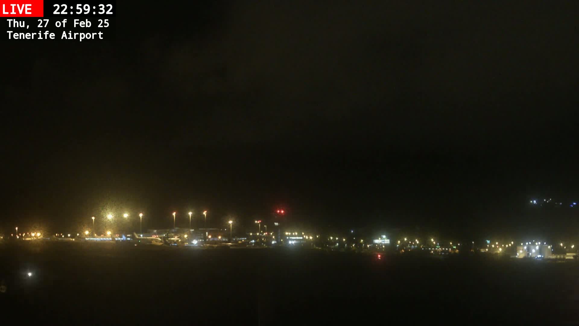 A nighttime view of an airport with dim lighting under a dark, overcast sky.