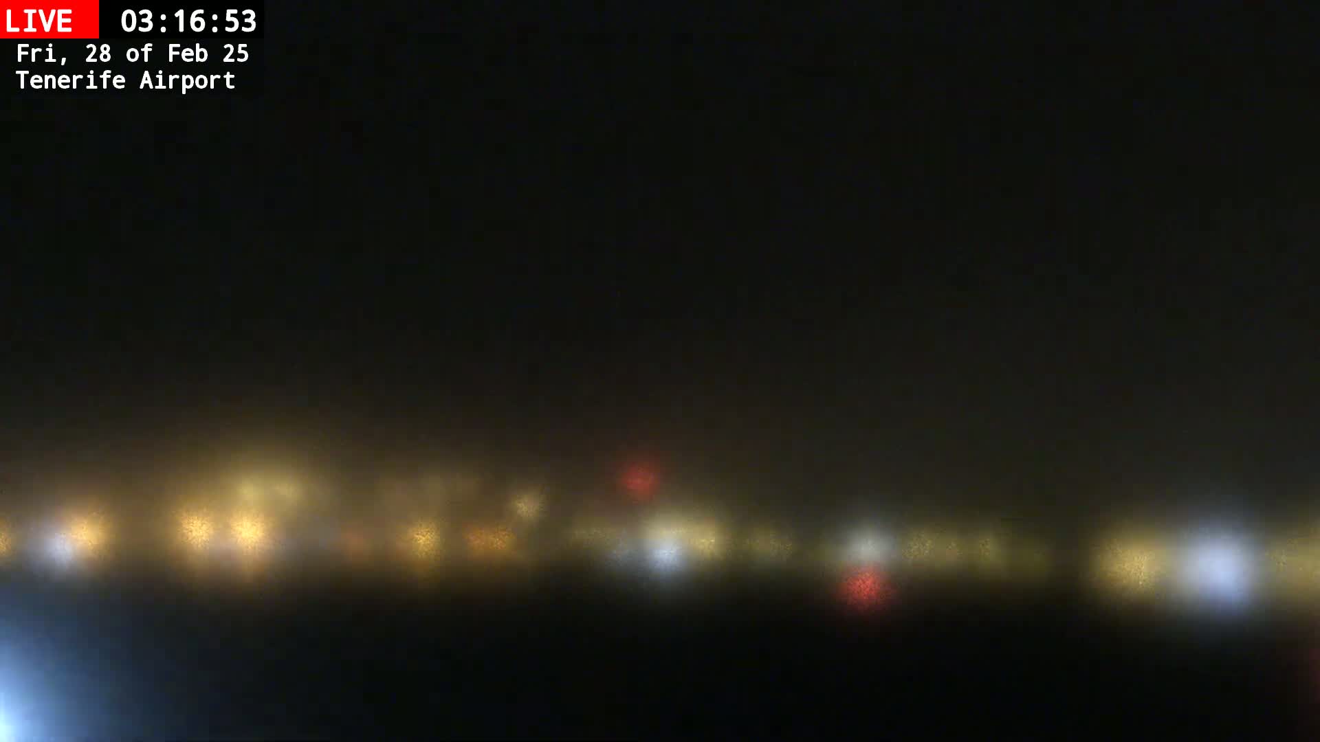 A hazy, foggy nighttime scene shows a line of blurry lights in the distance.