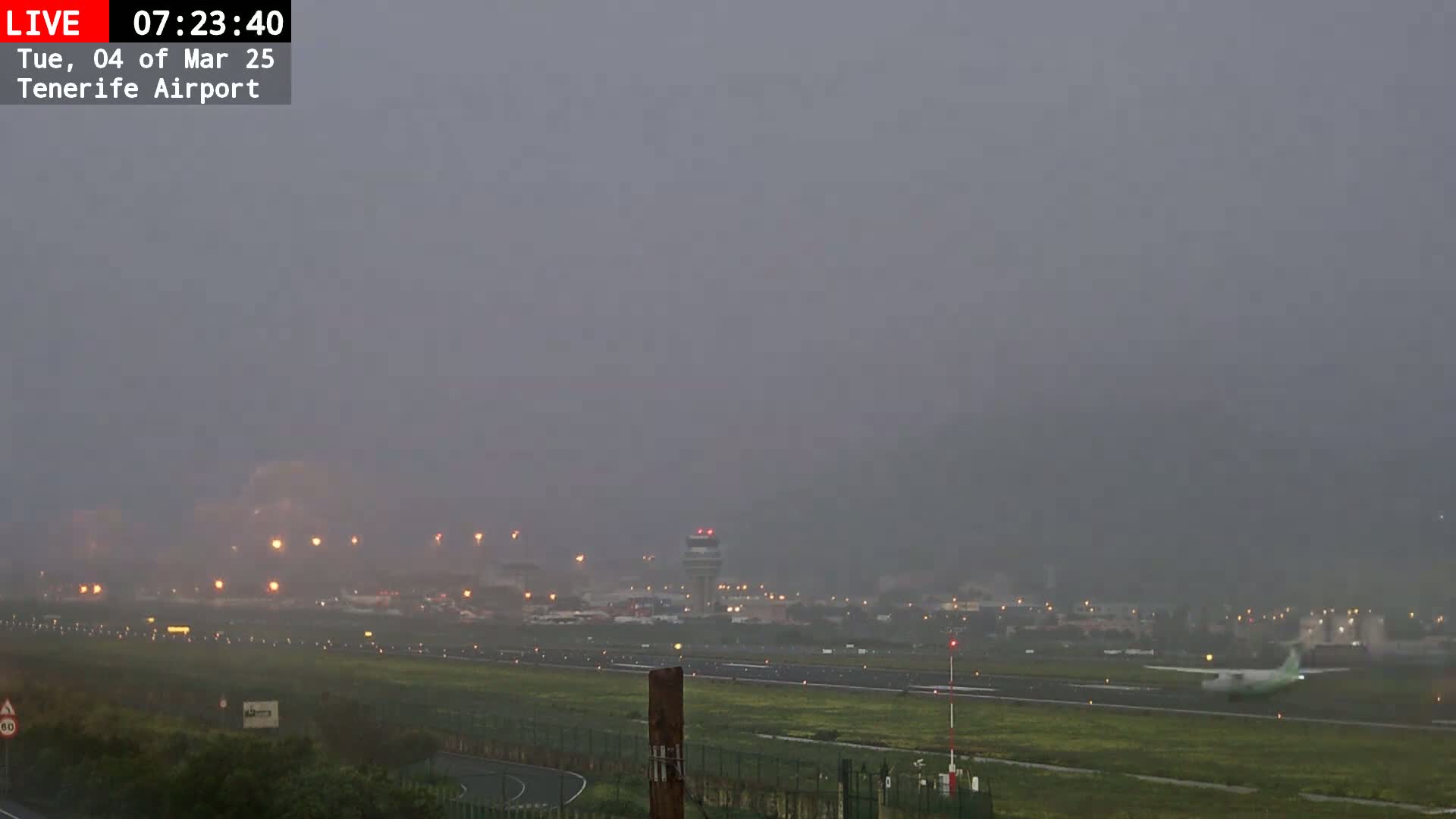 A small airplane taxis on a runway at an airport in foggy conditions.