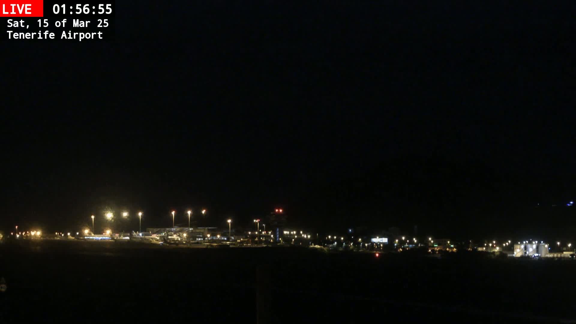 A nighttime view of an airport illuminated by numerous lights under a dark sky.
