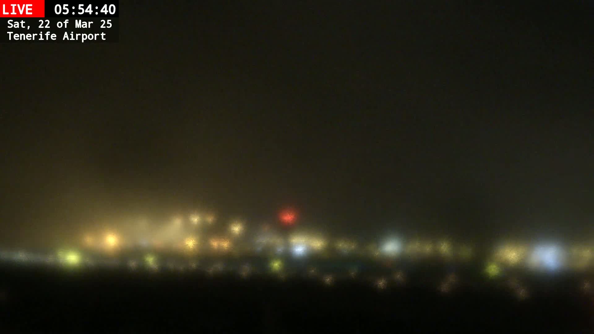 A blurry nighttime view of a foggy airport with distant lights.