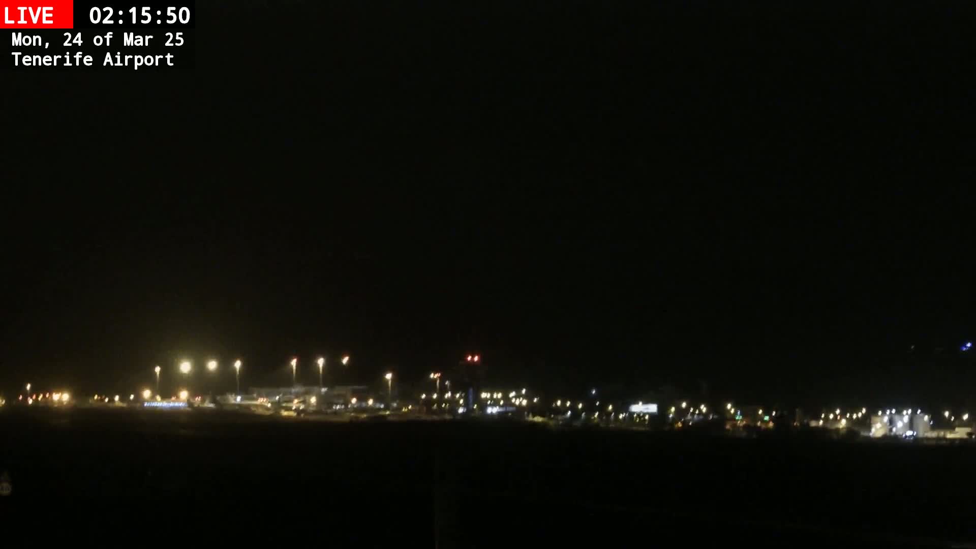 At night, the lights of an airport are visible against a dark sky.