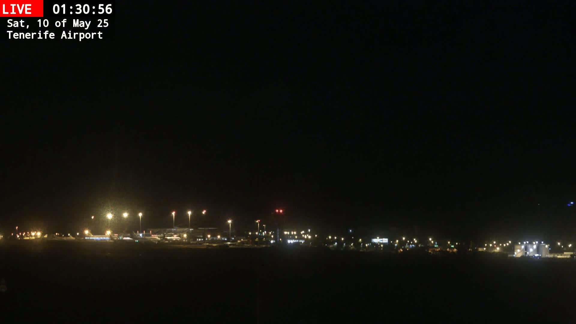 A nighttime long shot of an airport with its lights illuminated under a clear, dark sky.