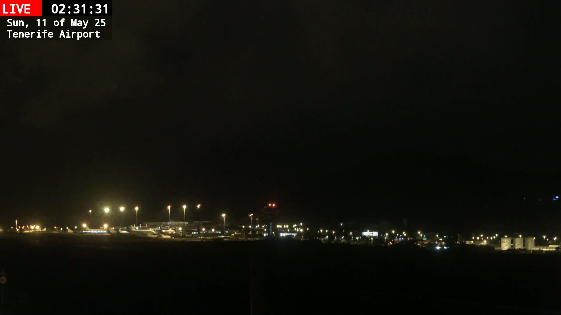 A nighttime, dimly lit airport is visible under a dark sky.