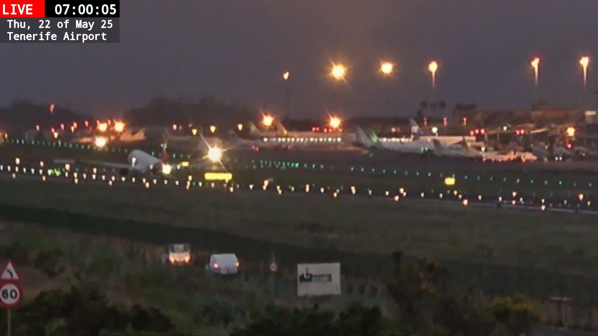 A nighttime view of an airport runway with several airplanes visible, under dark, possibly overcast conditions.