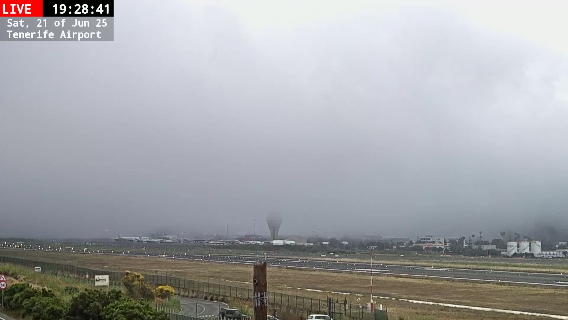A foggy view of an airport runway with several airplanes visible in the distance.