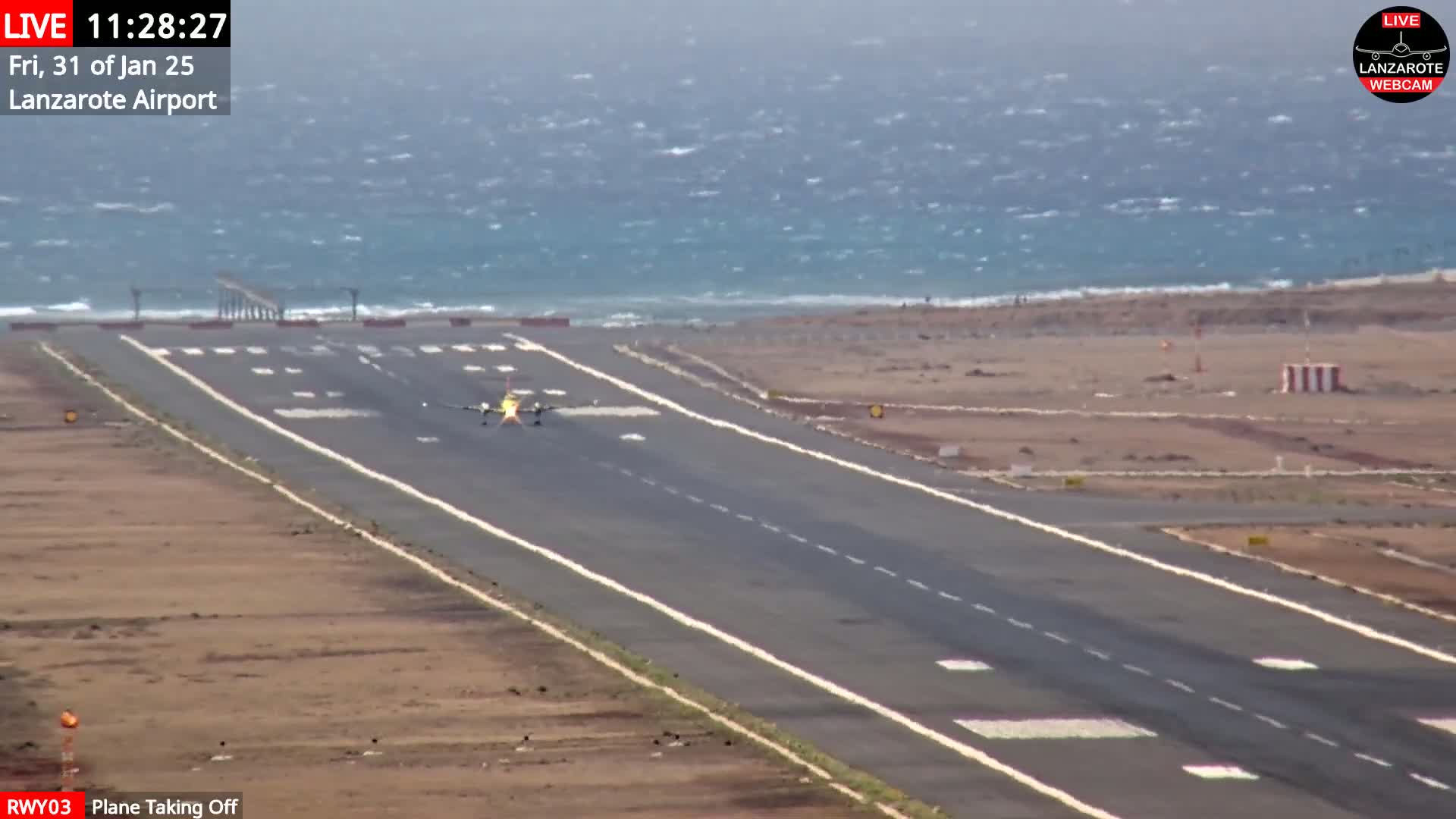 A plane takes off from a runway next to a windy ocean.