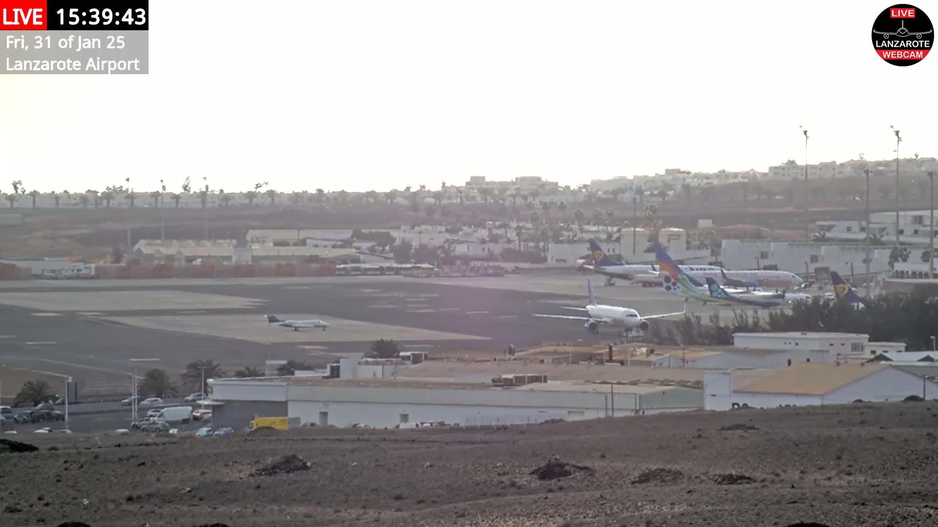 Several airplanes are parked on a tarmac at an airport on a hazy day.