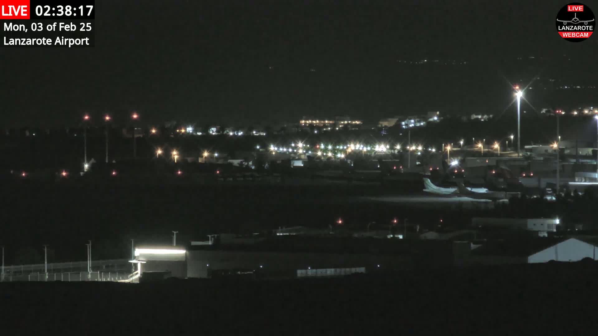 A nighttime long shot of an airport with a plane on the tarmac, under clear skies.
