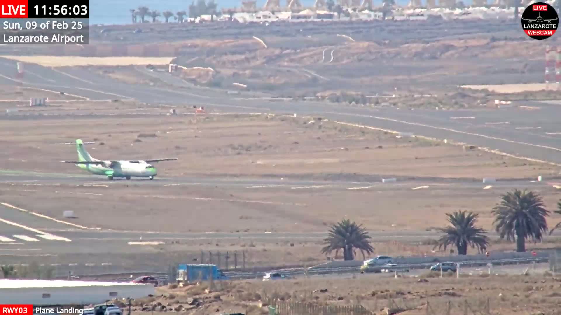A small passenger plane is landing on a runway at an airport on a sunny day.