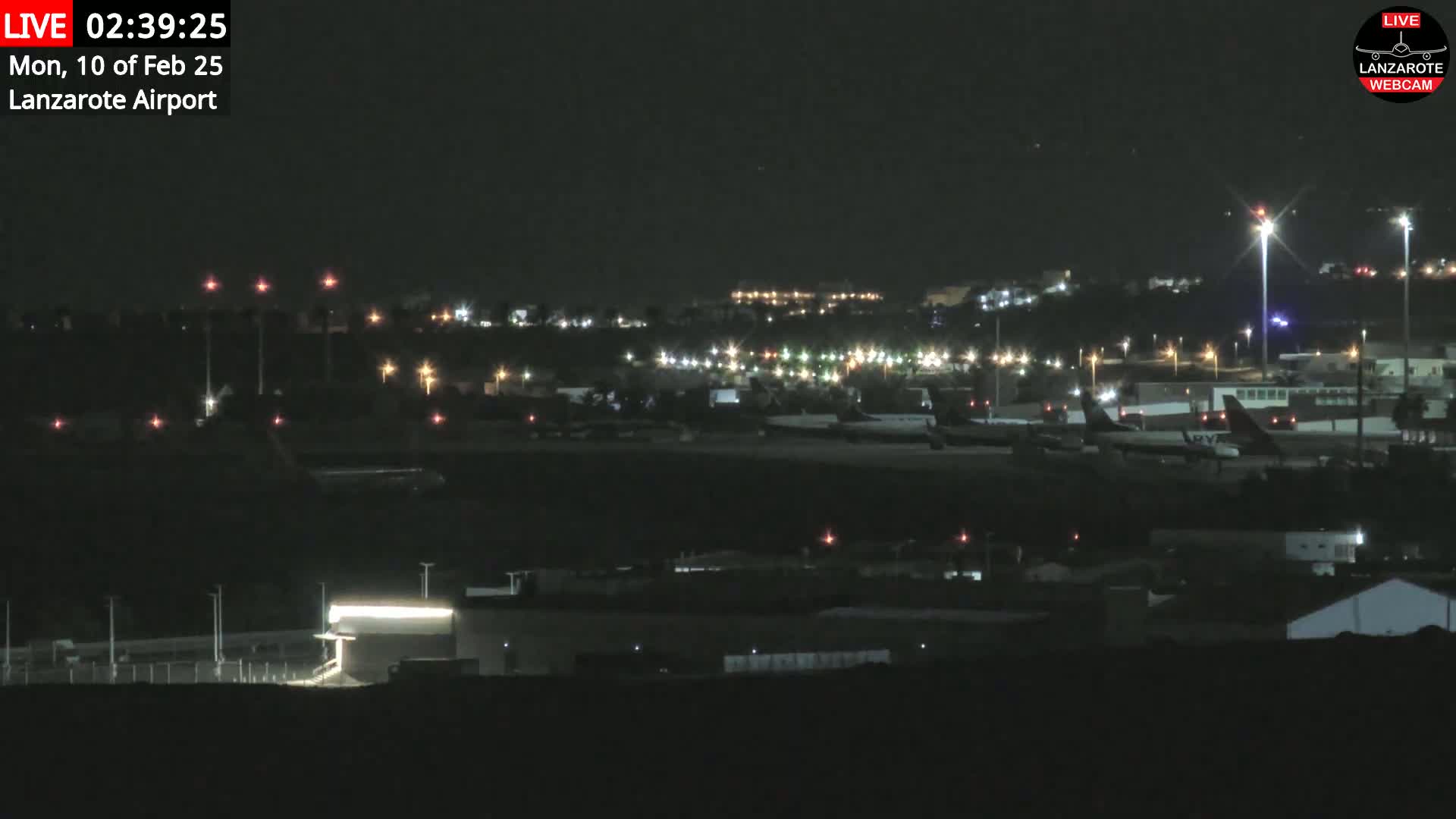 A nighttime long shot of an airport with several planes parked on the tarmac under a clear, dark sky.