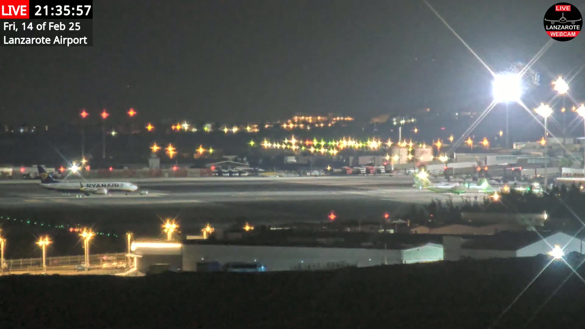 A Ryanair airplane is on the tarmac of a brightly lit airport at night.