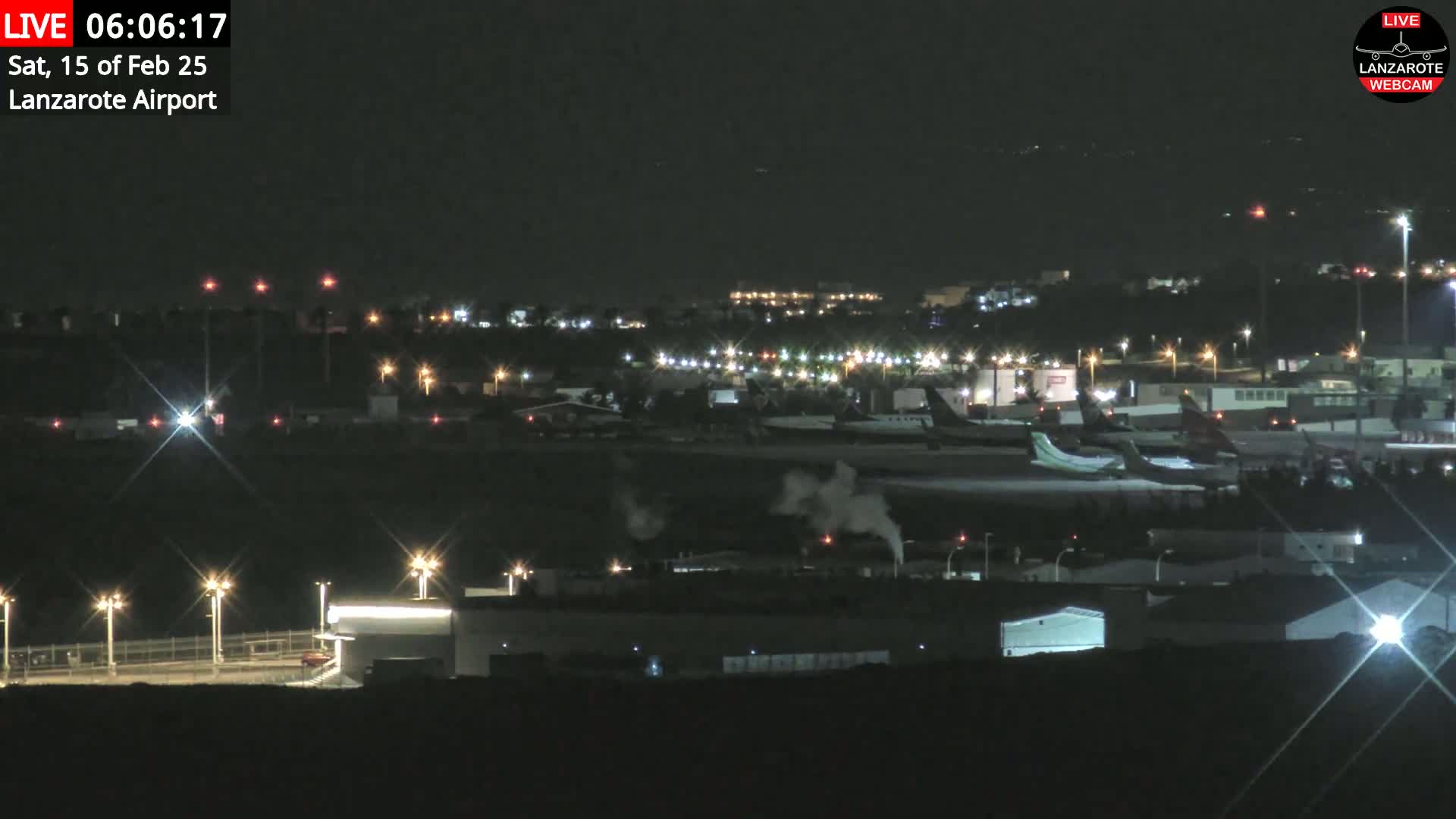 A nighttime view of an airport with several airplanes parked on the tarmac under a clear, dark sky.