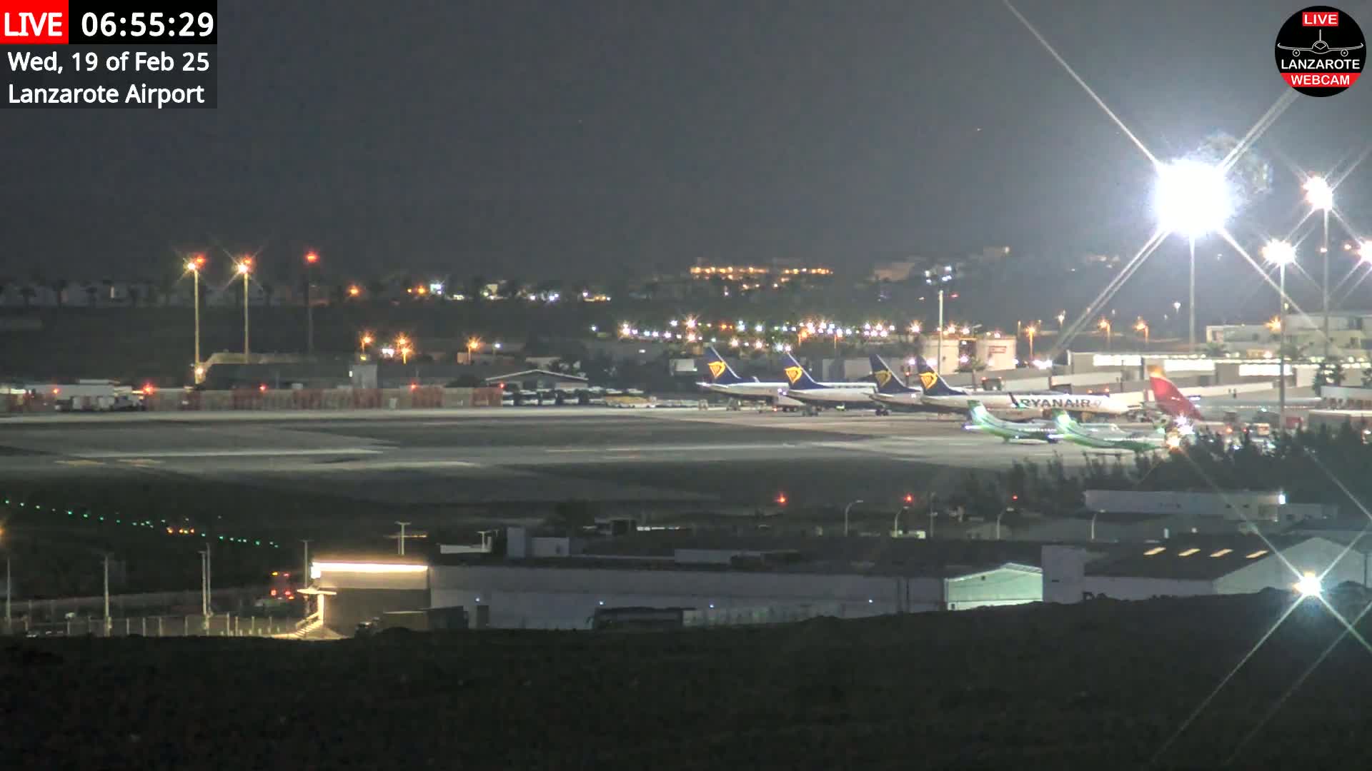 Several airplanes are parked on a brightly lit airport tarmac at night.