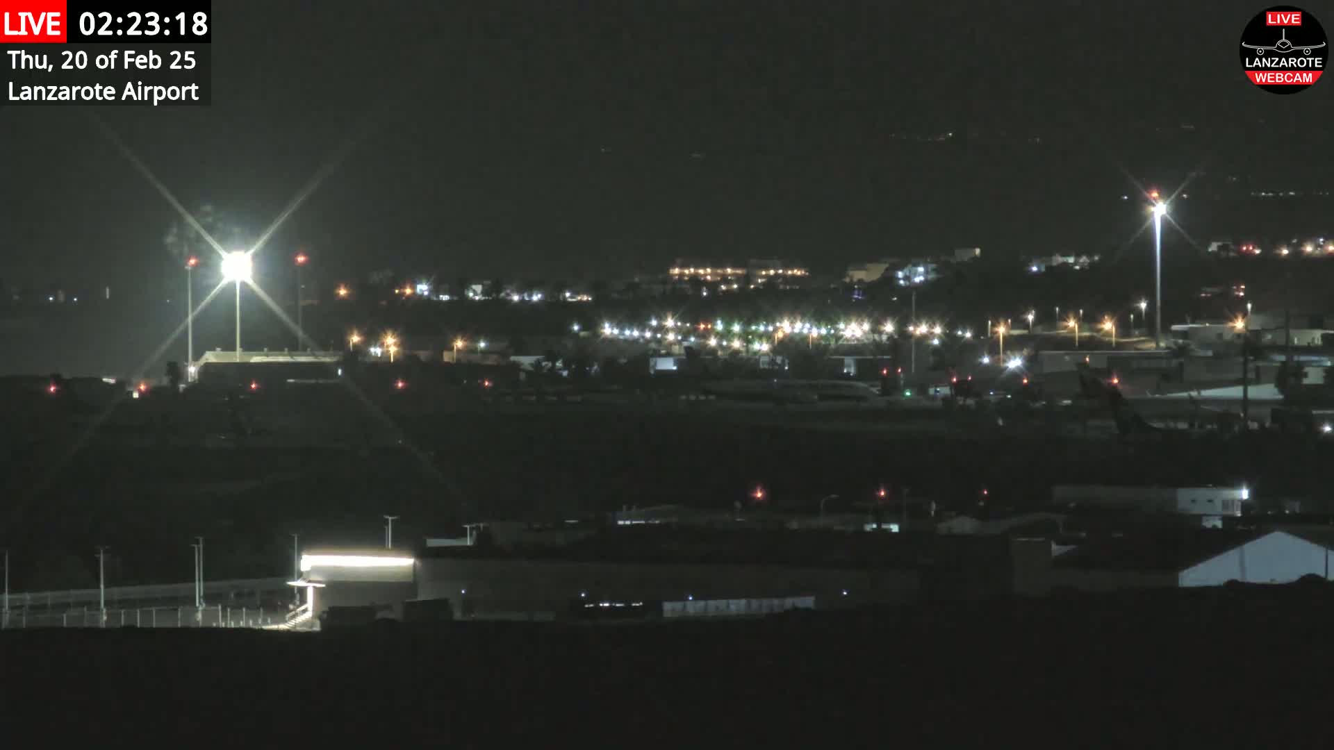 A nighttime, long-range view of an airport illuminated by lights, with a bright light source at the center.