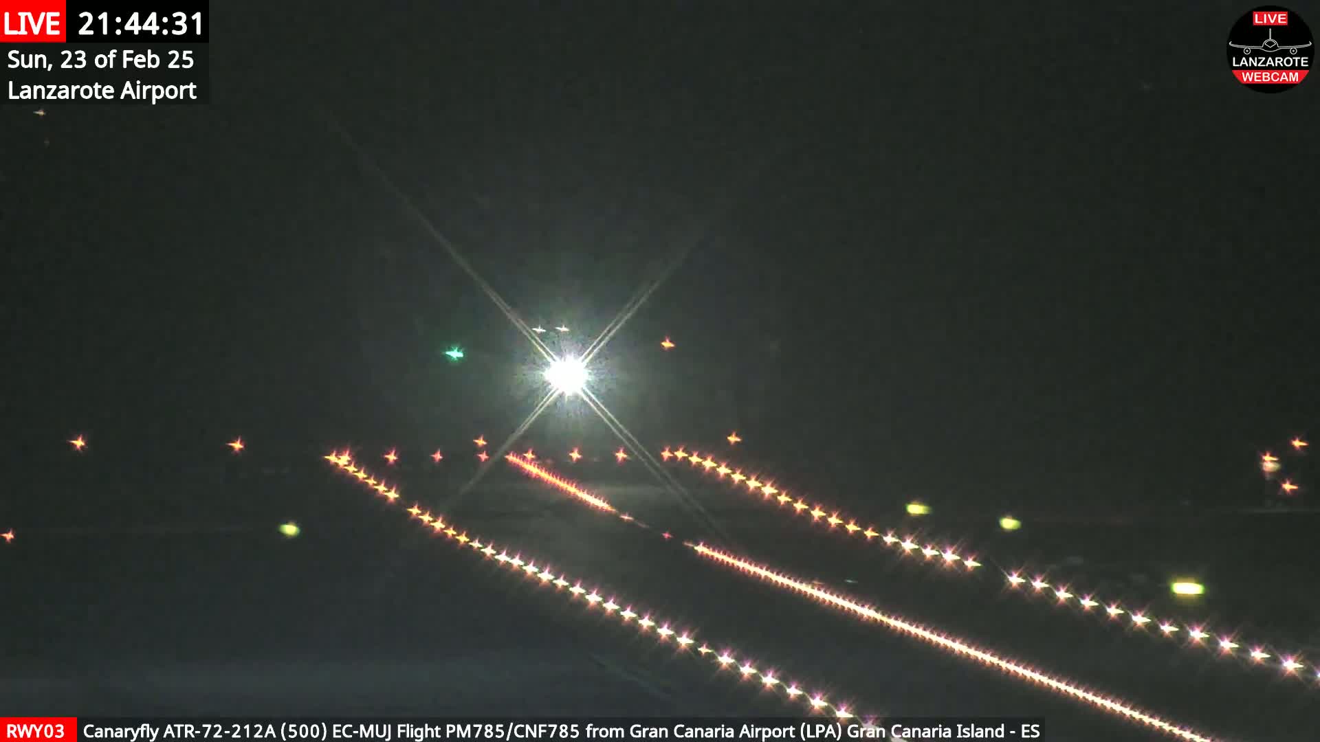 A nighttime view of an airport runway with lights illuminating the tarmac under a clear, dark sky.