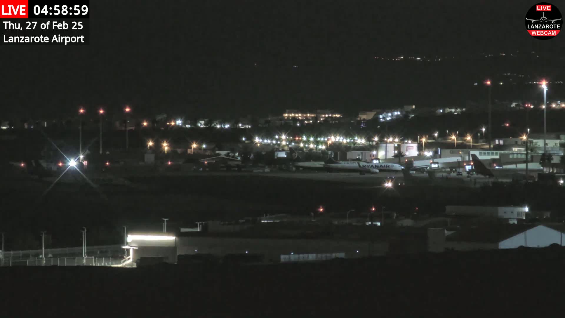 A nighttime view of an airport with several airplanes parked on the tarmac under clear skies.