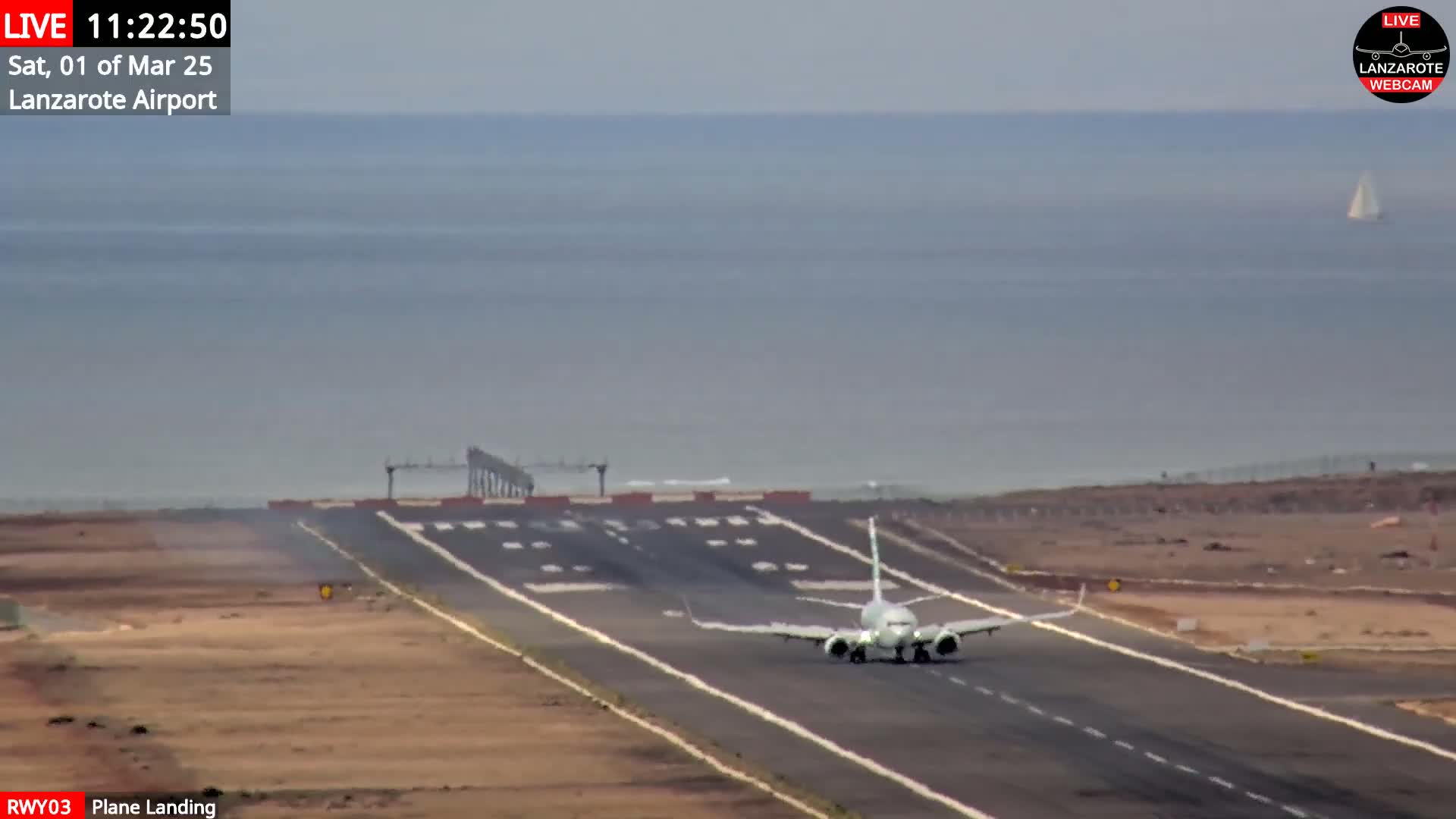 A commercial airplane is landing on a runway near a body of water under hazy conditions.
