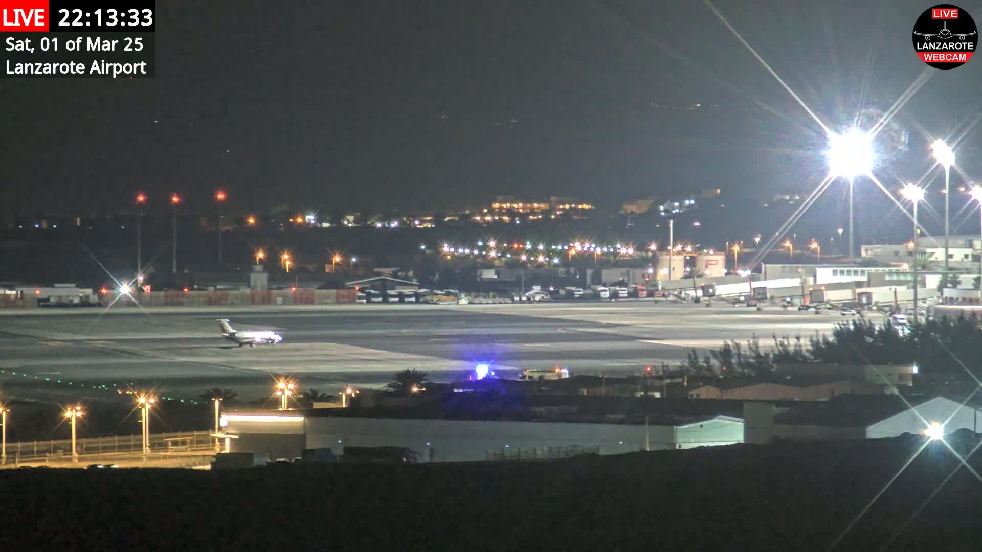 A small airplane sits on a brightly lit airport tarmac at night.