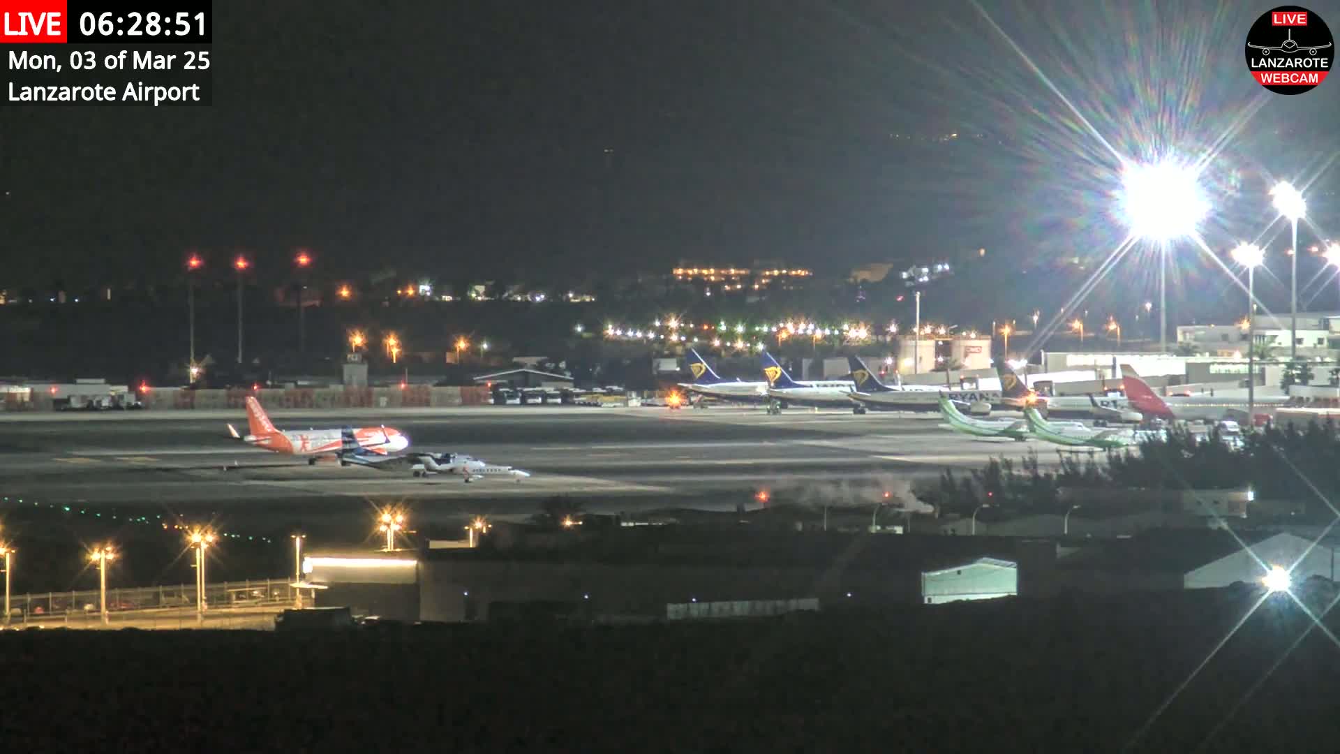 A nighttime view of an airport tarmac with several airplanes parked under bright lights.