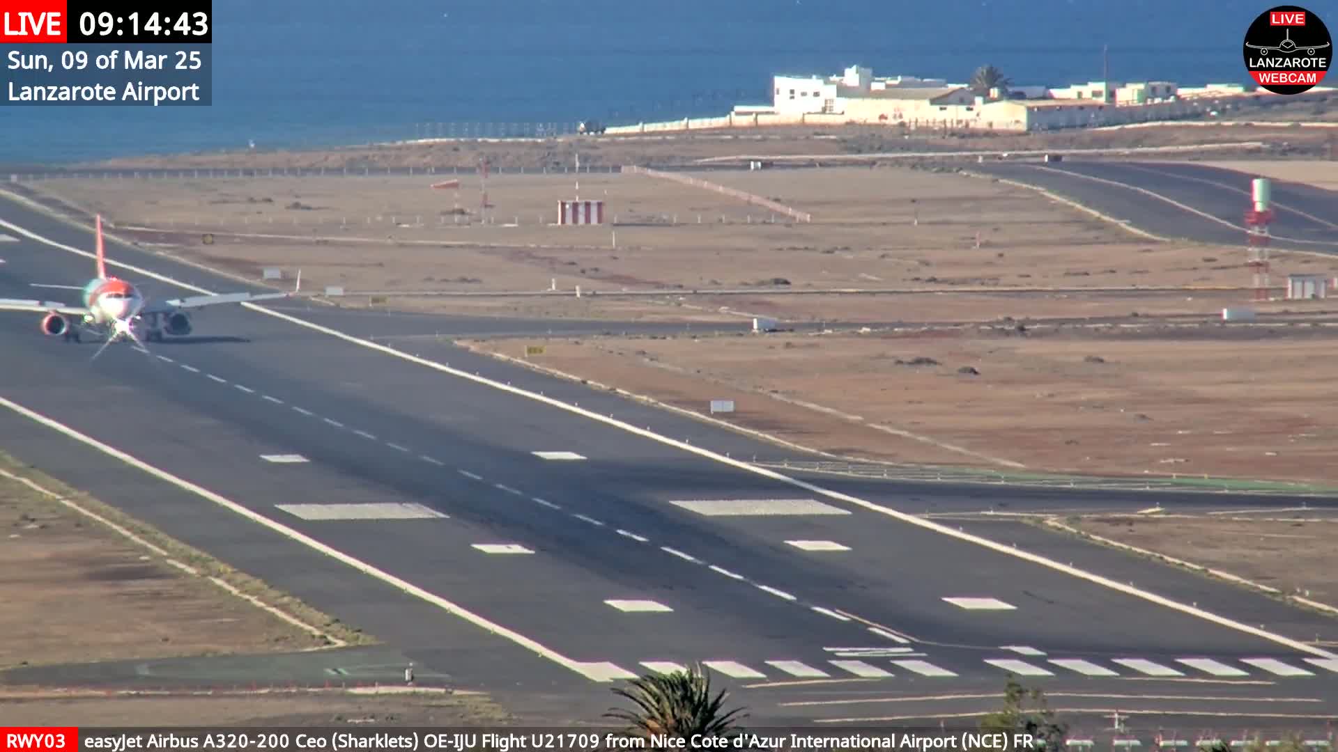 A passenger plane is taxiing on a runway at an airport next to a body of water under sunny conditions.