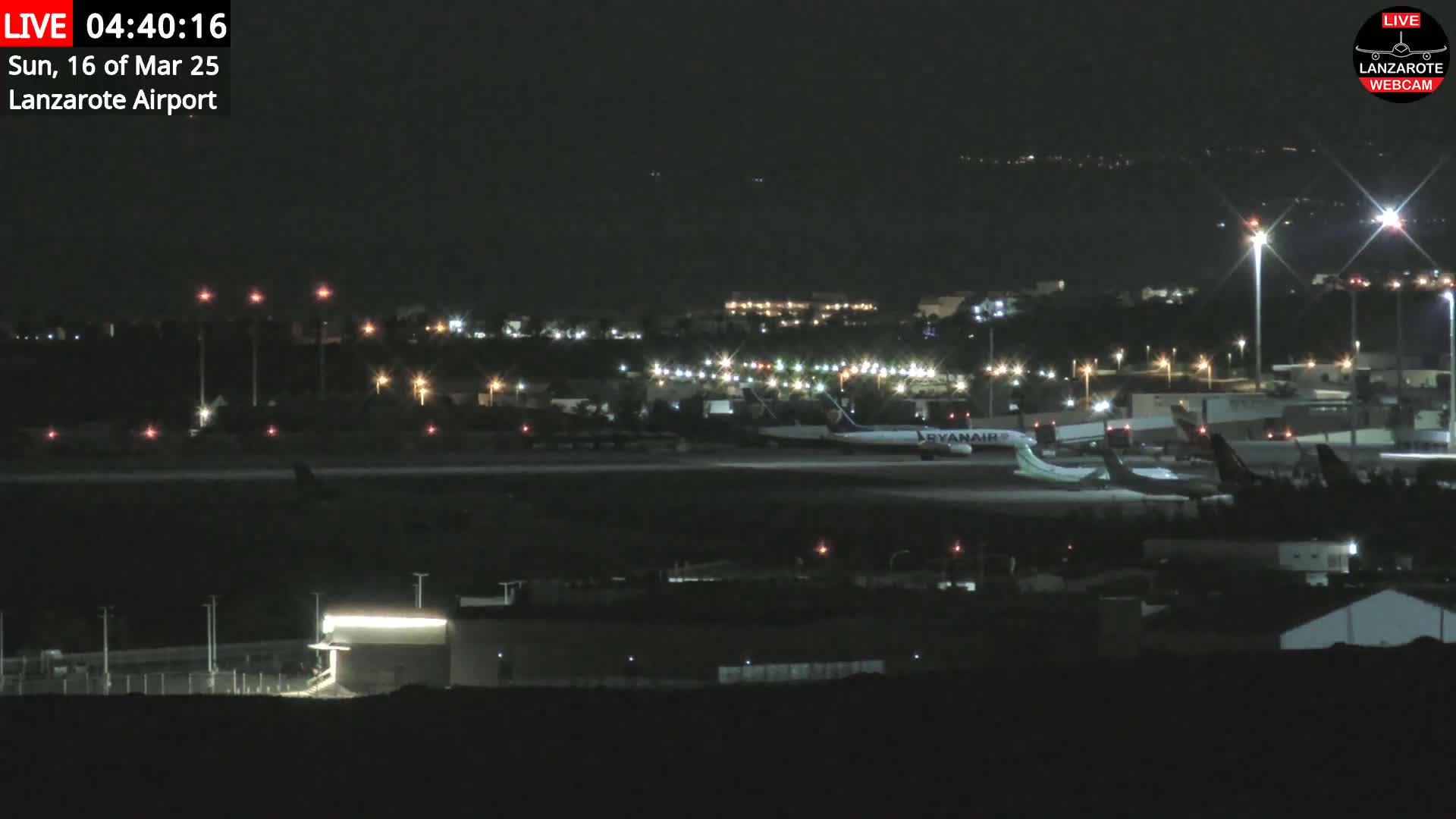 Several airplanes are parked on a dark airport tarmac at night under clear skies.