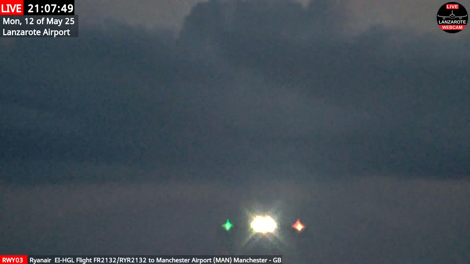 A plane's lights are visible at night under a dark, cloudy sky.