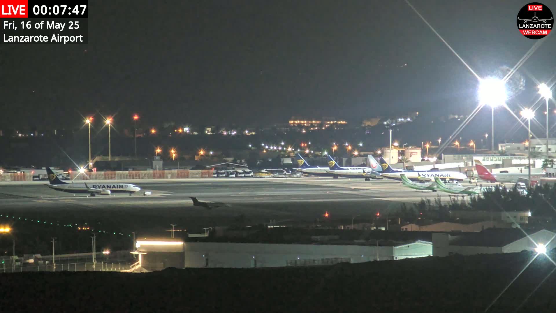 A white airplane is landing on a runway near a body of water under sunny skies.
