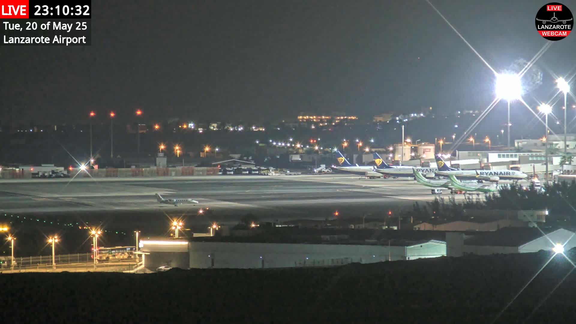 Several airplanes are parked on a brightly lit airport tarmac at night.
