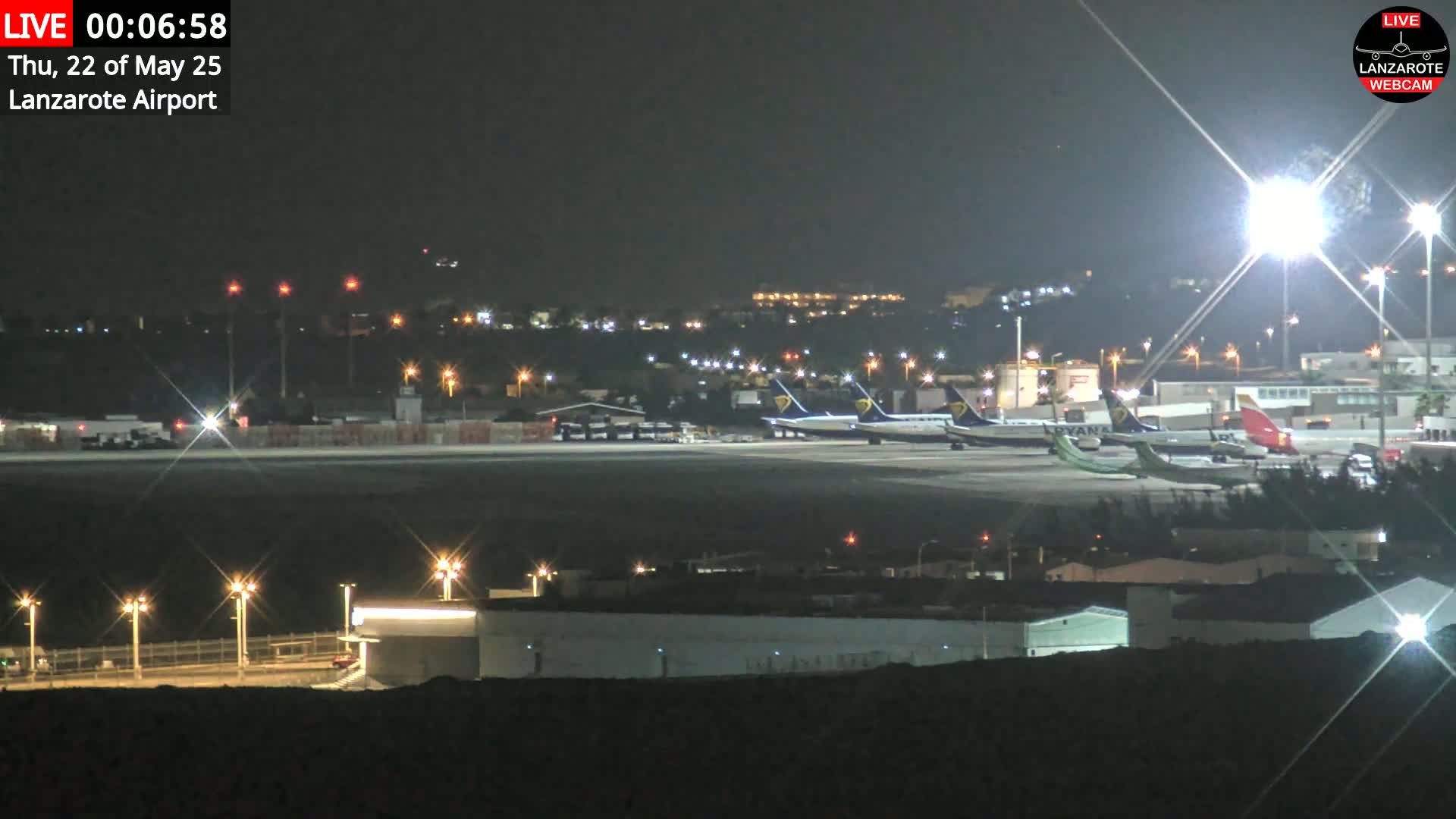 Several airplanes are parked on a tarmac at night under bright lights.