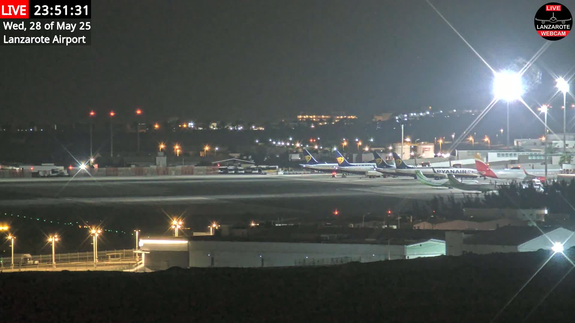 A nighttime view of an airport tarmac with several airplanes parked under bright lights.