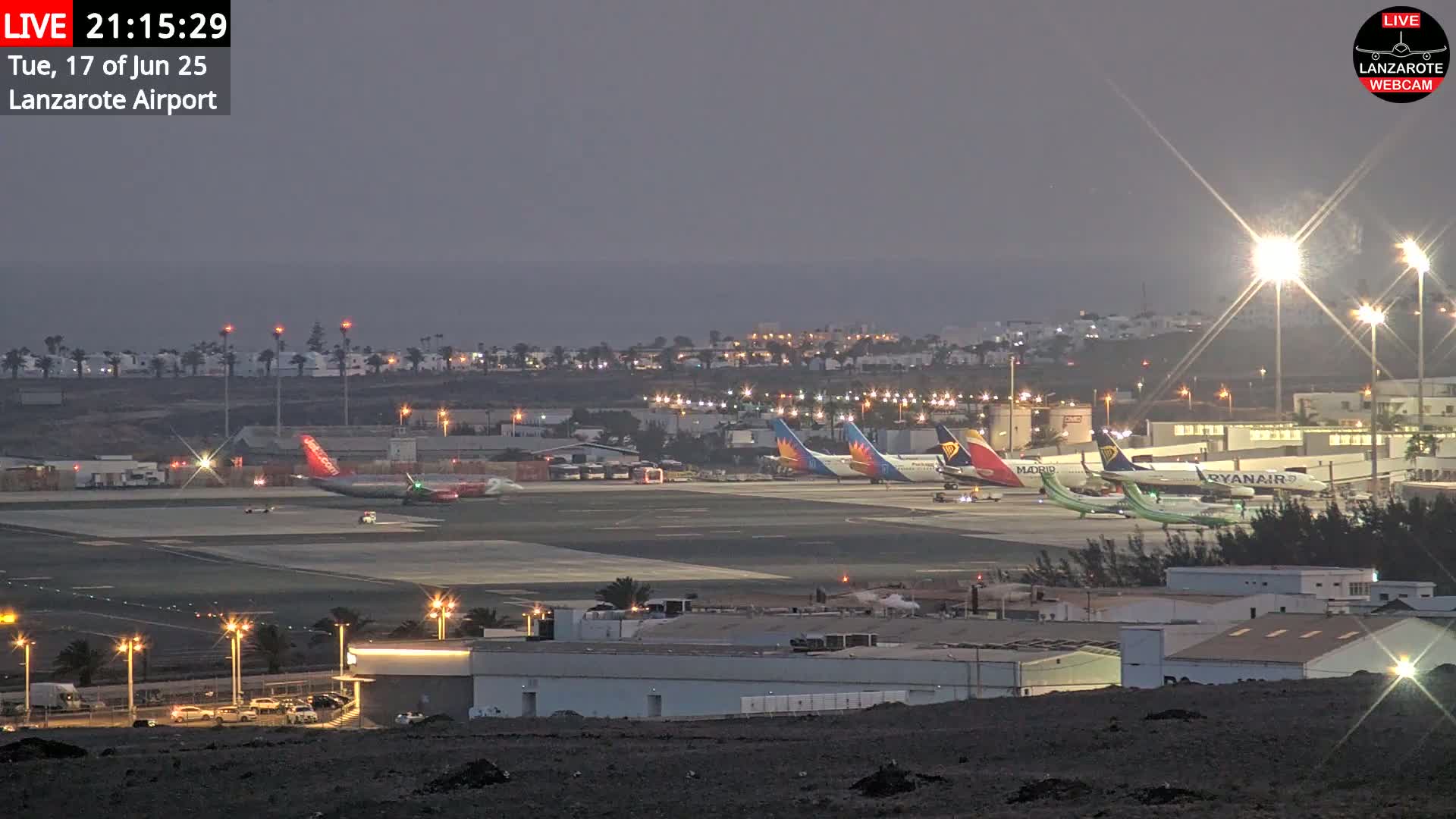 Several airplanes are parked on an airport tarmac at twilight under partly cloudy skies.