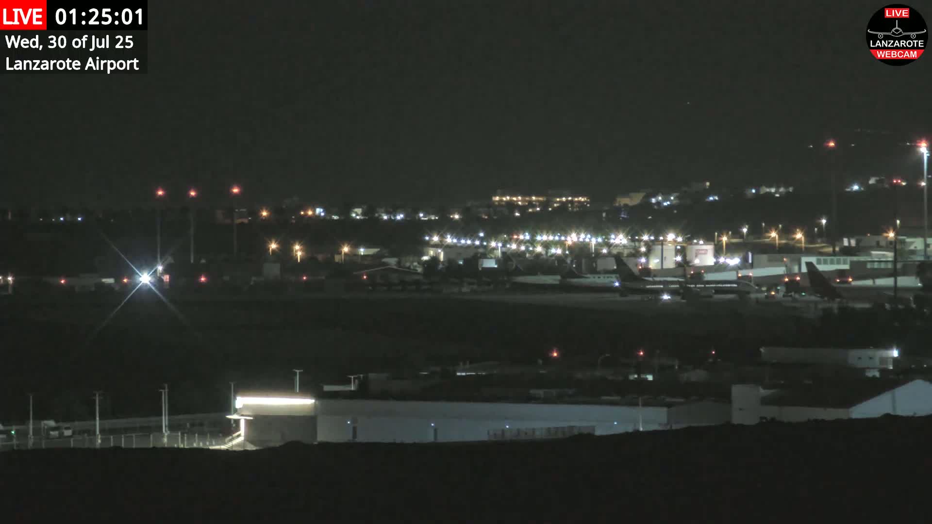 An airport tarmac with a private jet, surrounded by buildings and a distant ocean under hazy skies.