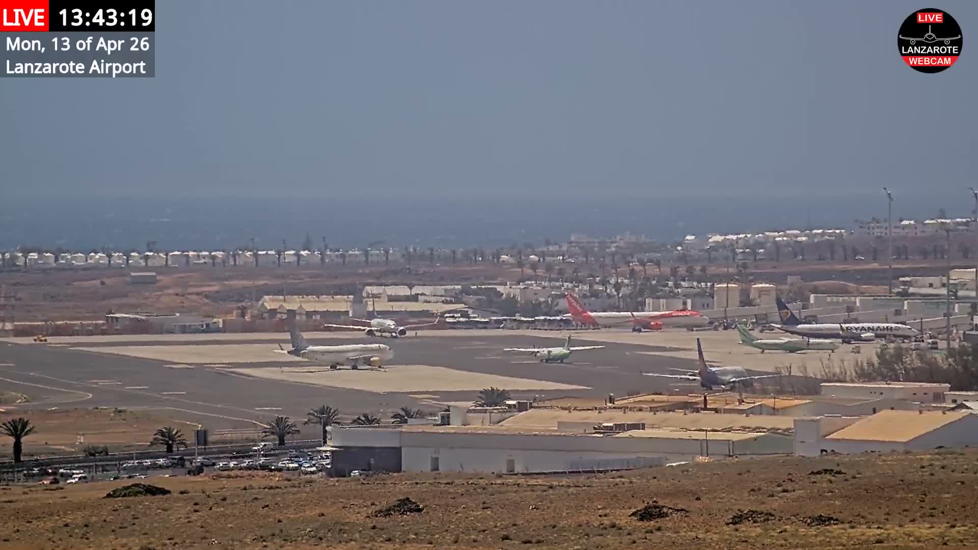A commercial airplane with bright, starburst landing lights is centered on an airport runway next to the ocean under a gloomy, overcast sky.