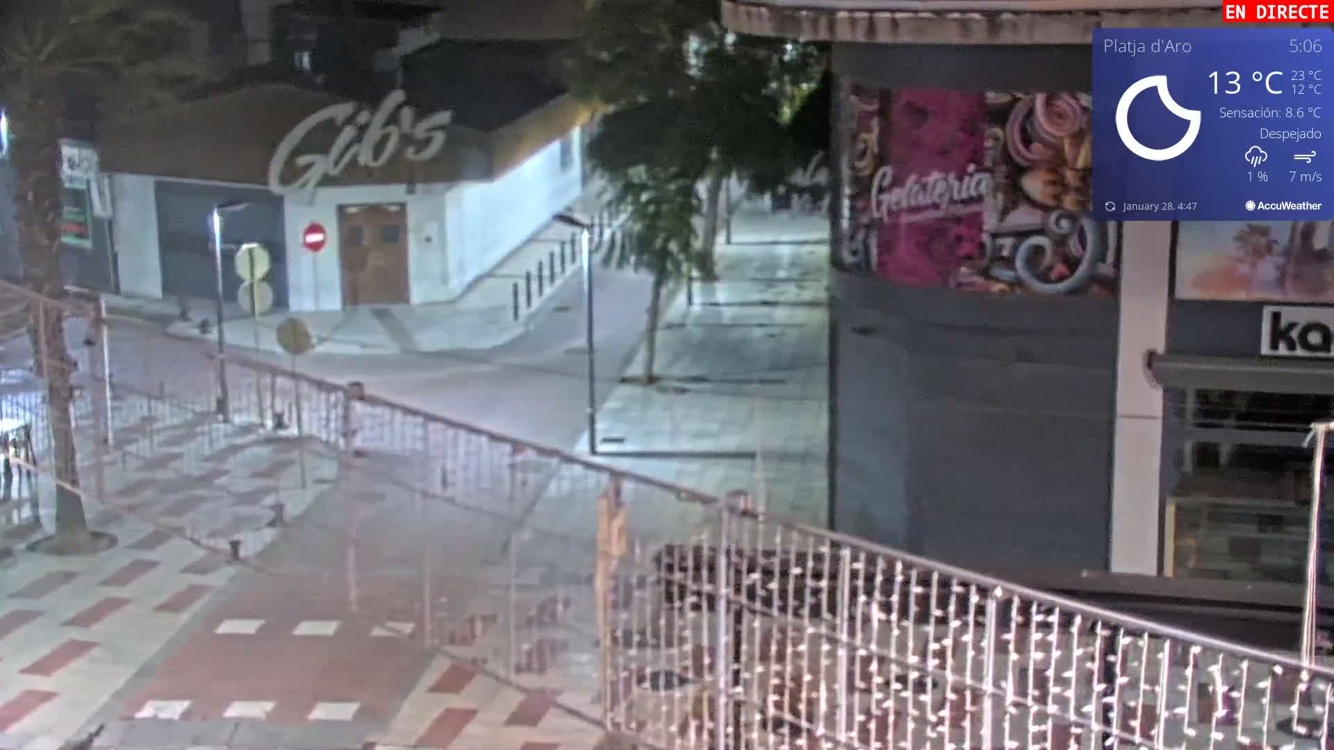 A nighttime street scene shows a mostly empty plaza with a few buildings, including one with a sign that says "Gib's" and another with a "Gelateria" sign, under clear skies.