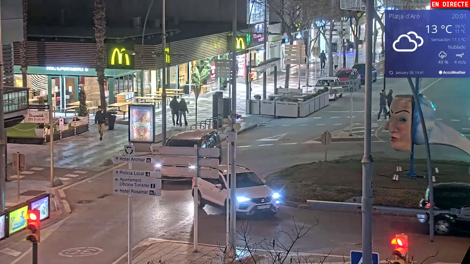 A nighttime street scene shows a McDonald's restaurant and several cars at an intersection under cloudy skies.