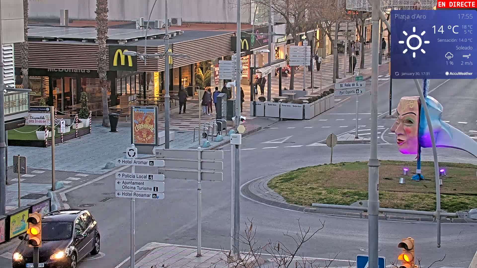 A street scene shows a McDonald's and other shops under a sunny sky with a light breeze.