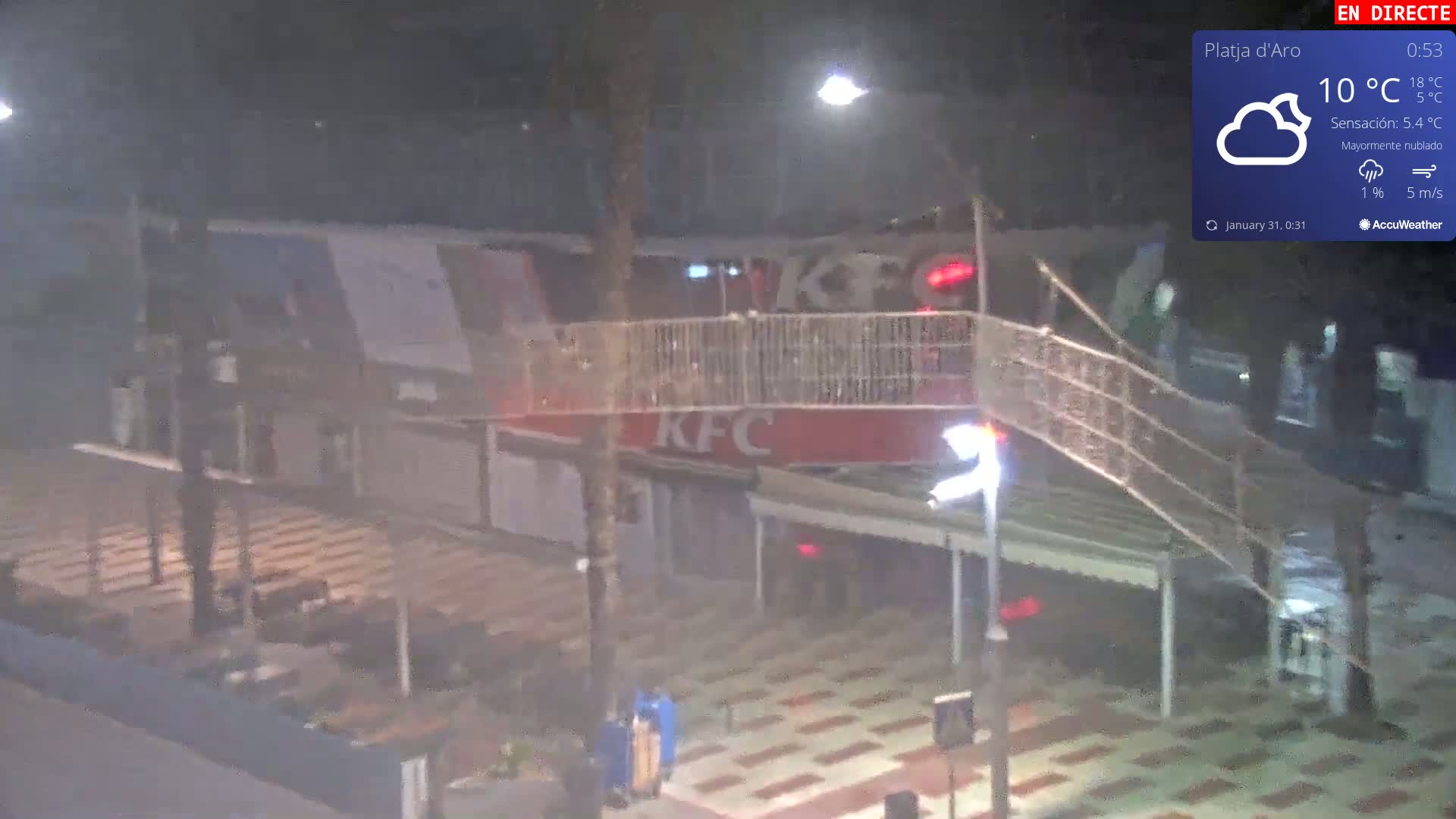 A mostly cloudy night scene shows a pedestrian walkway above a street-level KFC restaurant.