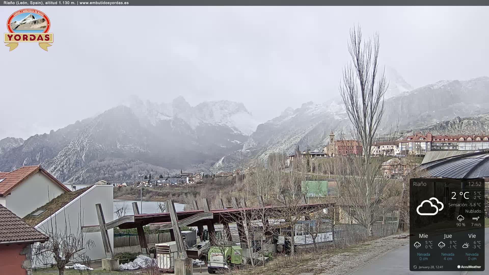 A snow-dusted mountain range overlooks a small town under an overcast sky.
