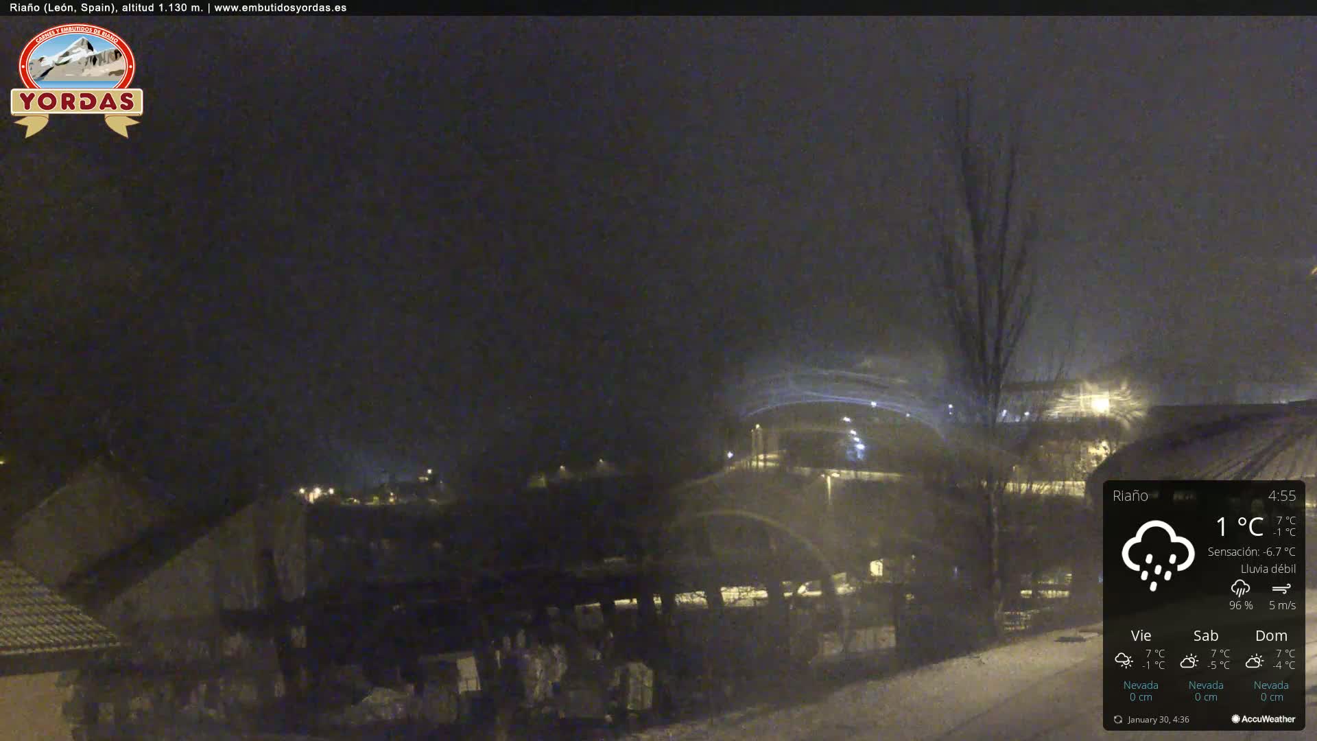 A nighttime scene of a snow-covered town under a light snowfall.