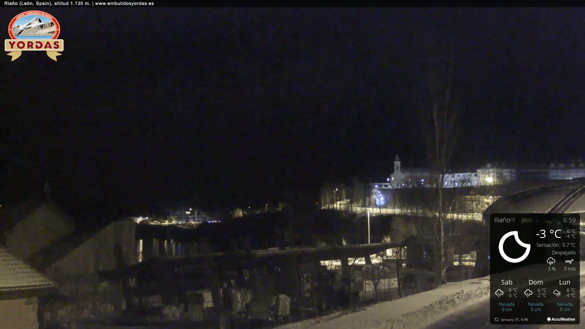 A nighttime view of a snow-covered town under a clear, cold sky.