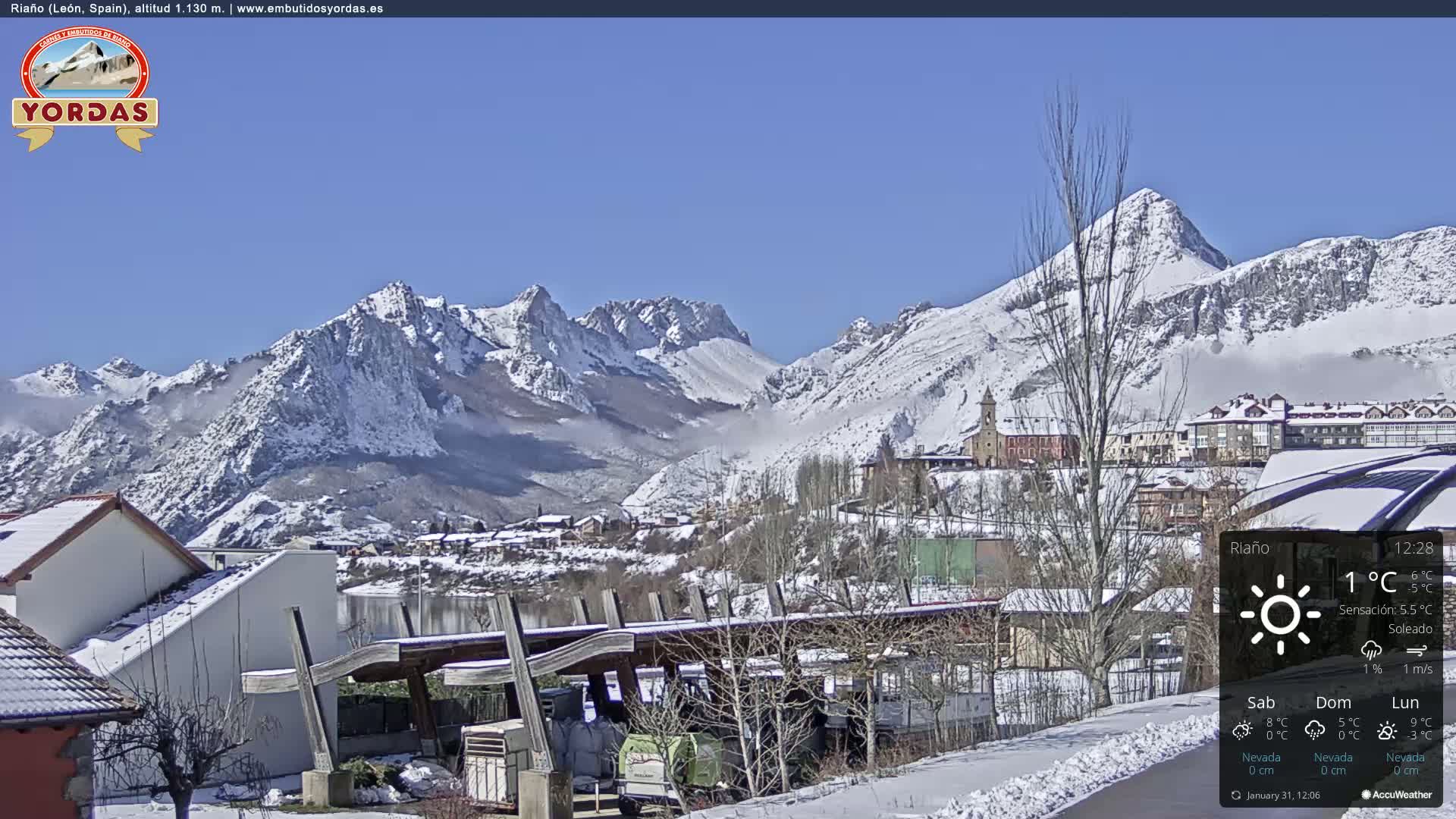 A sunny, snow-covered mountain village nestled in a valley between snow-capped peaks.