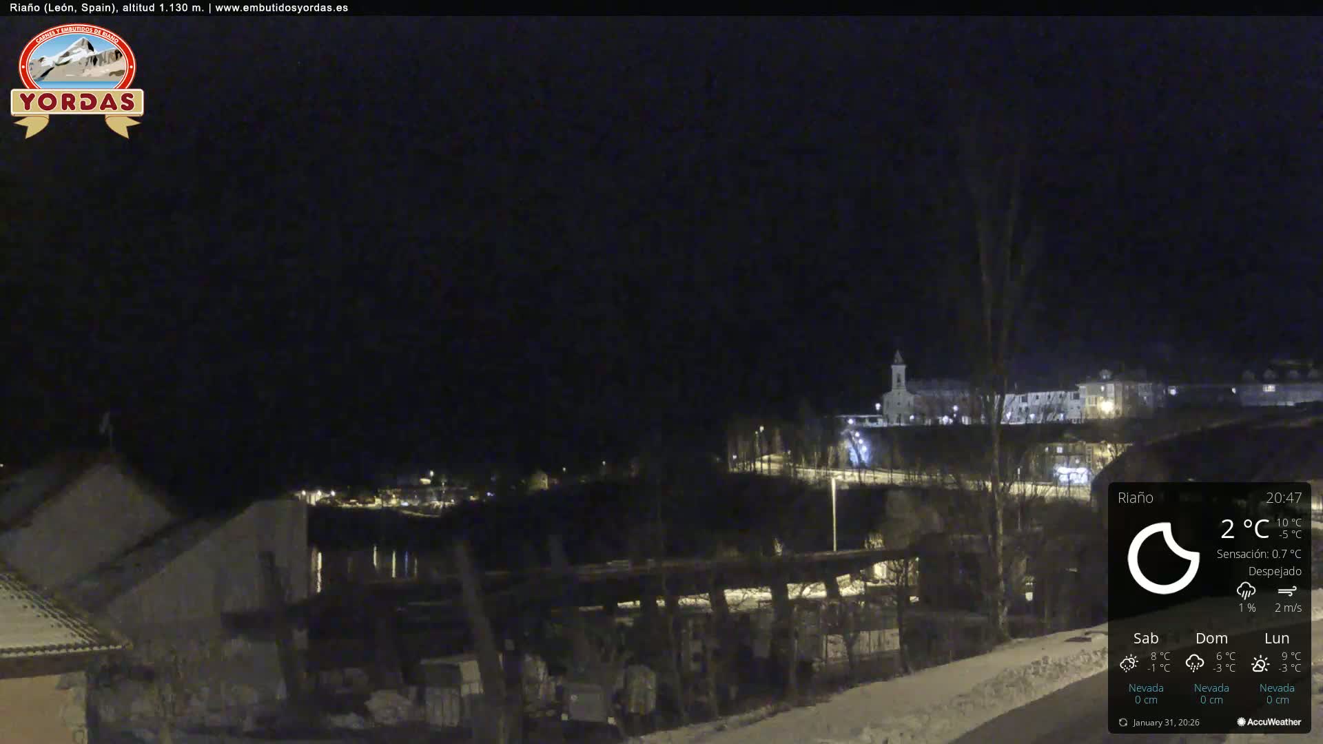 A nighttime view of a snow-covered town illuminated by streetlights, under a clear sky.