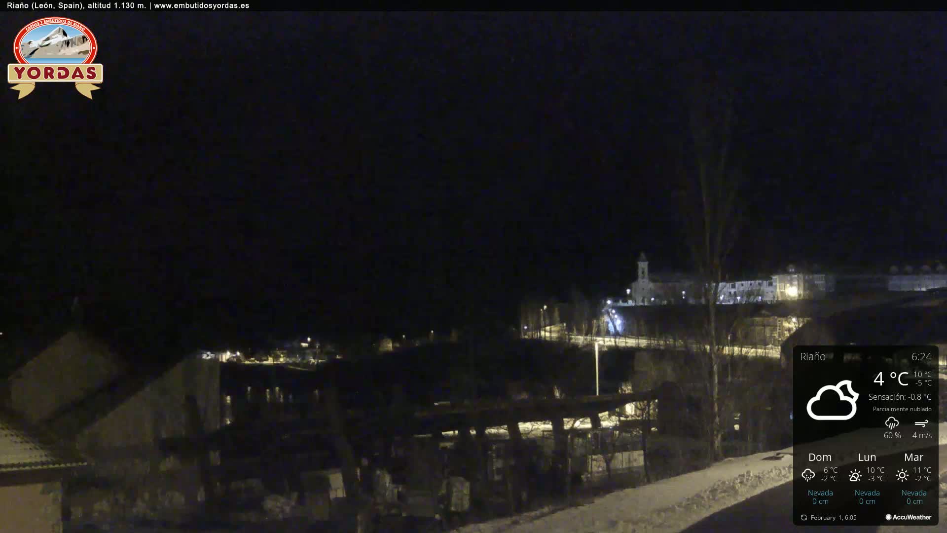 A nighttime view of a snow-dusted town under a partly cloudy sky.