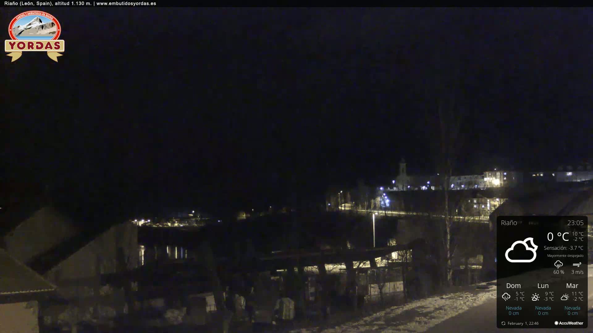 A nighttime view of a snow-covered town, under a mostly clear sky.